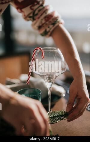 Eine Person hält ein Glas mit einem roten und weißen Stock in der Hand. Die Person bereitet sich darauf vor, den Wein zu trinken Stockfoto