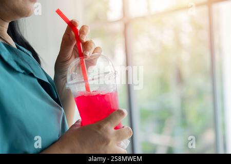 Nahaufnahme einer Frau, die eisrotes Erfrischungsgetränk mit Strohhalm im Glas trinkt. Speisen- und Getränkekonzept. Stockfoto