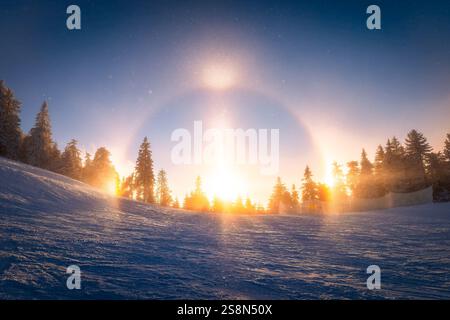 Fangen Sie die Schönheit eines seltenen Sonnenlichts über einer verschneiten Skipiste in Poiana Brasov ein. Perfekt für Wintersportler, Naturliebhaber und Liebhaber atmosphärischer Phänomene Stockfoto