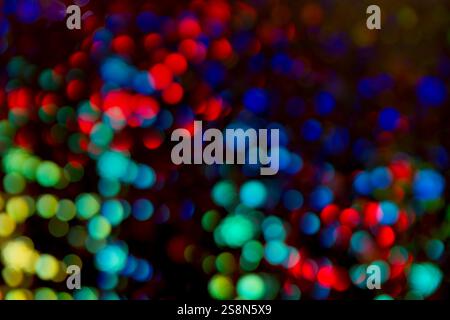 Vibrant Light Symphony, eine bunte Auswahl an bunten Bokeh-Lichtern, die auf einem tiefschwarzen Hintergrund verstreut sind. Die leuchtende Palette umfasst lebendige Rottöne. Stockfoto