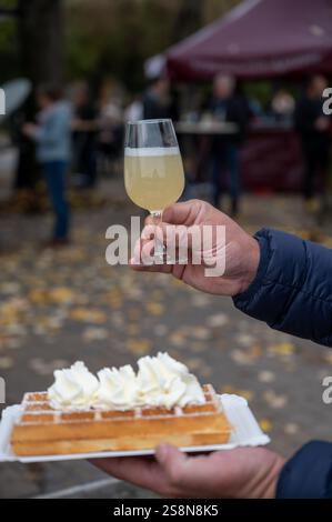 Weinfest in Schengen, Luxemburg, französischen oder luxemburgischen Waffeln mit Schlagsahne und einem Glas Jungwein, der im Herbst im Freien gegessen wird Stockfoto