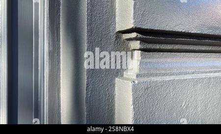 Detaillierte Ansicht eines architektonischen Gebäudeschmucks mit feinem Stuckverzierungen, strukturierter Oberfläche und natürlichem Licht, das Schatteneffekte erzeugt. Stockfoto
