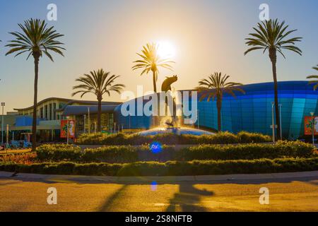 Long Beach, Kalifornien - 15. Januar 2025: Dolphin Fountain im Aquarium of the Pacific, umgeben von Palmen und beleuchtet von Sonnenuntergang Stockfoto