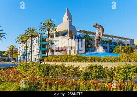 Long Beach, Kalifornien - 15. Januar 2025: Blick auf den Dolphin Fountain neben einzigartiger Architektur im Aquarium of the Pacific, eingerahmt von Palmen Stockfoto
