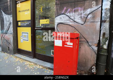 KRAKAU, POLEN - 11. NOVEMBER 2024: Paketkasten Paczkomat und traditioneller roter Briefkasten von Poczta Polska, Wettbewerb der Zusteller in Krakau, Polen. Stockfoto