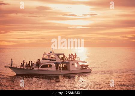 Gruppe von Familie und Freunden, die Einen wunderschönen Sonnenuntergang auf Einer kleinen Yacht in Manado, Indonesien, genießen Stockfoto