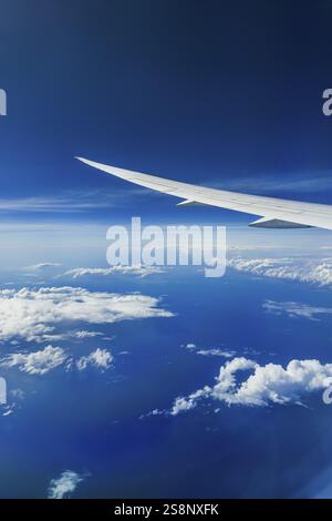 Blick aus dem Flugzeugfenster während eines Fluges über Indien mit der Fluggesellschaft Etihad. Blauer Himmel und Wolkenstrukturen über dem Meer, Flügel einer Boeing 787 Luft Stockfoto