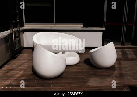 Moderne weiße Möbel auf einer hölzernen Terrasse in einem minimalistischen Außenbereich Stockfoto