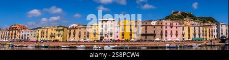 Panoramafoto mit Häusern und Promenade am Fluss Temo, Gäste in den Restaurants und Sonnenschirmen, blauer Himmel mit Wolken, Castello Malaspina, Castel Stockfoto