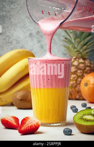 Ein Glas frischer, köstlicher, farbenfroher Smoothie und Obst im Hintergrund Stockfoto