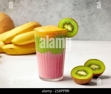 Ein Glas farbenfrohen Smoothie und frisches Obst auf dem Küchentisch Stockfoto