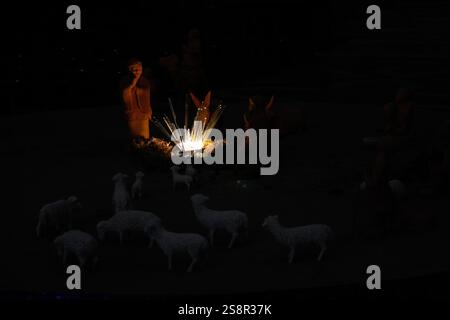 Beleuchtete Krippe mit Figuren und Schafen in dunkler Atmosphäre Stockfoto