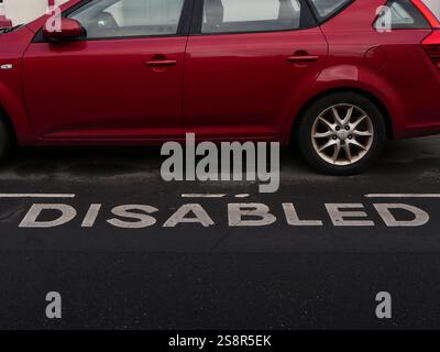 Parkplatz auf einem Behindertenparkplatz in einer Wohnstraße vor einer Terrassenanlage. Stockfoto