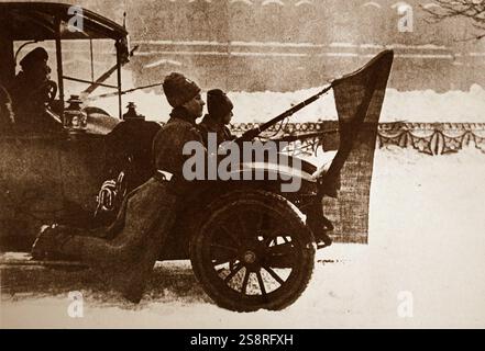Foto von Soldaten reiten auf dem Schmutzfänger eines Autos mit roten Fahnen an ihren Gewehren in Petrograd (St. Petersburg) während der Februarrevolution von 1917. Vom 20. Jahrhundert Stockfoto