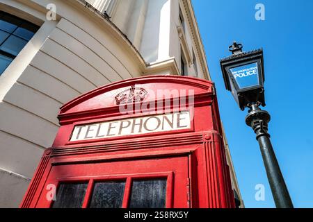Tradition britische rote Telefonbox und Polizeilaterne in London, England. Details der Stadtarchitektur und Hintergrund mit blauem Himmel. Stockfoto
