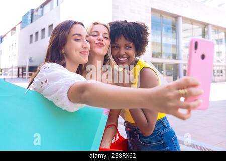 Drei glückliche junge Frauen machen gemeinsam ein Selfie in einer Stadtstraße Stockfoto