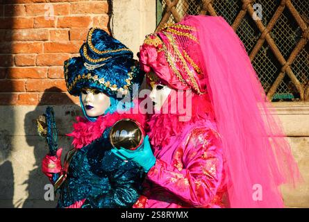 VENEDIG, ITALIEN - 16. FEBRUAR 2015: Zwei Masken (mit einer Kugel und einer Reflexion des Dogenpalastes) auf dem Markusplatz während des traditionellen Karnevals. Carniva Stockfoto