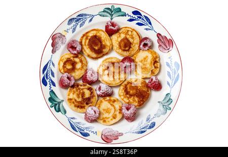 Teller mit traditionellen niederländischen Pffertjes, auch Mini-Pfannkuchen genannt, mit Himbeeren und Puderzucker isoliert auf weiß Stockfoto