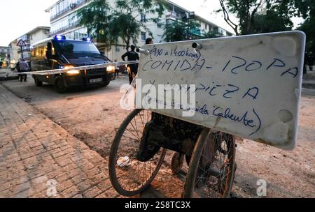 Nachtszene mit Polizisten, die nach den DANA-Überschwemmungen auf den Straßen patrouillieren, und die kostenlose Mitteilung der Verteilstelle am Rollstuhl. Alfafar, Spanien. Stockfoto