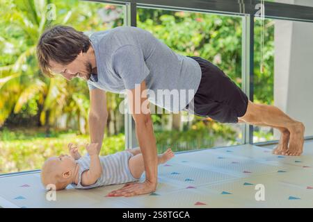 Ein Vater arbeitet mit seinem 3 Monate alten Baby, macht Liegestütze und hält inne, um sein Kind zu küssen. Ein fröhlicher und herzerwärmender Moment, der Fitness kombiniert Stockfoto