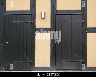 Holztür in einer Fachwerkscheune. Die Türbeschläge und die tiefe Holzmaserung verleihen dem Bild einen rustikalen Charme Stockfoto