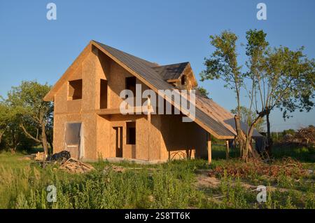 Bau eines neuen energieeffizienten SIP-Hauses mit Holzrahmen. Unbearbeitetes Holzwohngebäude mit Panelwand im Landbereich. Stockfoto