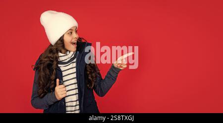 ausdruck positiver Emotionen. Wintermode. Zeigefinger auf Kopierraum. Emotionales Kind Stockfoto