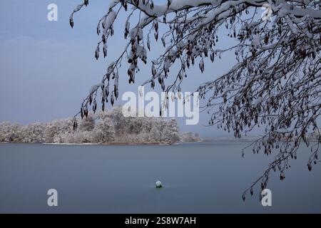 Die Schönheit eines Wintertages zeigt sich in diesem Bild des Galve-Sees in Trakai, Litauen. Die Sonne scheint hell über dem Himmel und strahlt ein warmes Leuchten aus Stockfoto