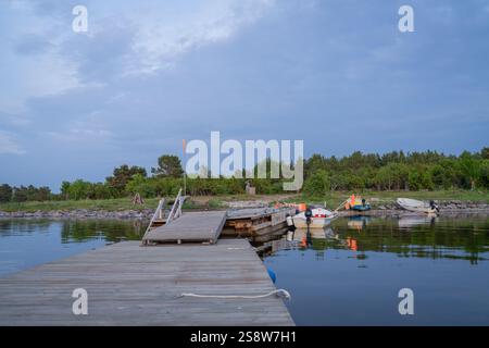 Fischerboote mit Netzflaggen am Pier. Angelbootpier und Boote am Meer am Abend. Stockfoto