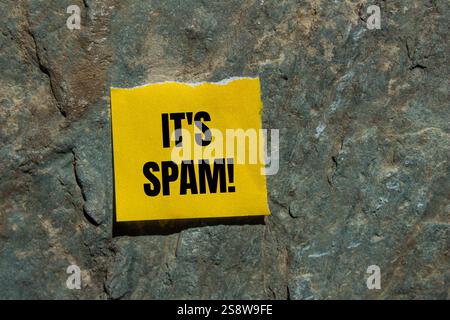 Es ist eine Spam-Nachricht, geschrieben auf zerrissenem gelbem Papierstück mit Steinhintergrund. Konzeptionell ist das Spam-Symbol. Kopierbereich. Stockfoto