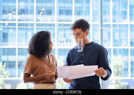 Ein geschäftiger Geschäftsmann und eine Geschäftsfrau stehen im Büro und reden über Dokumente. Stockfoto