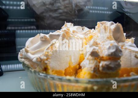 Eine Glasschale gefüllt mit einem Dessert mit Lemon Meringue Pie. Das Dessert wird in Stücke geschnitten, wodurch eine gelbe und weiße Füllung entsteht Stockfoto