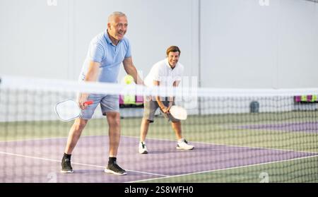 Älterer Mann spielt Pickleball im Team mit männlichem Partner im Haus Stockfoto