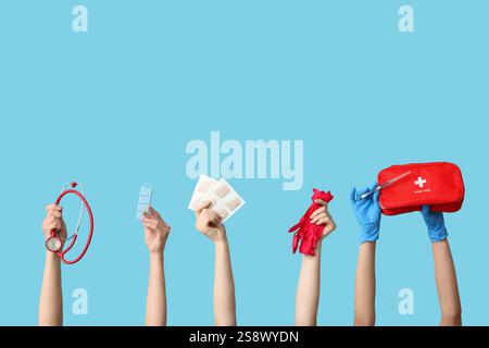 Weibliche Hände mit Senfpflastern, Stethoskop, Pillenbox, Handschuhen, Spritze und erste-Hilfe-Set auf blauem Hintergrund Stockfoto