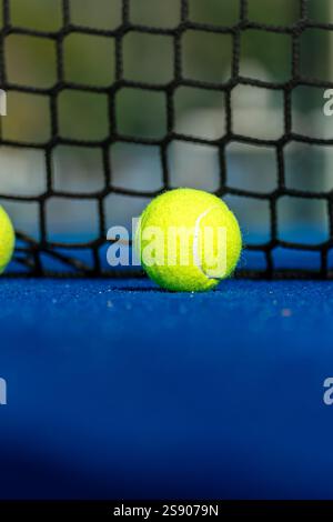Blauer Paddle-Tennisplatz, Blick auf zwei Bälle in der Nähe des Netzes. Selektiver Fokus. Hintergrund zum Racket-Sport Stockfoto