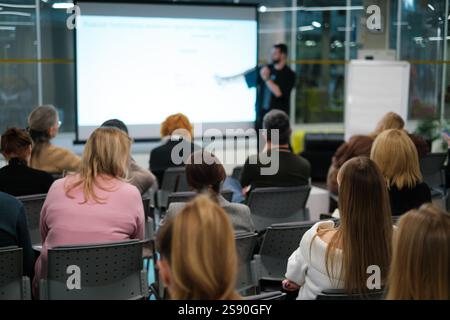 Das Publikum hört aufmerksam der Präsentation im Konferenzraum zu und konzentriert sich dabei auf das Lernen und die emotionale Bindung im professionellen Umfeld. Stockfoto