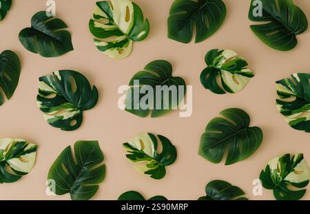 Trendiges Sommermuster aus grünen tropischen Blättern auf sandfarbenem Hintergrund. Minimales kreatives Konzept. Flaches Lay-Bild mit exotischem Hintergrund. Stockfoto