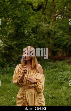 Frau in gelbem Leinenkleid, umgeben von Wildblumen Stockfoto