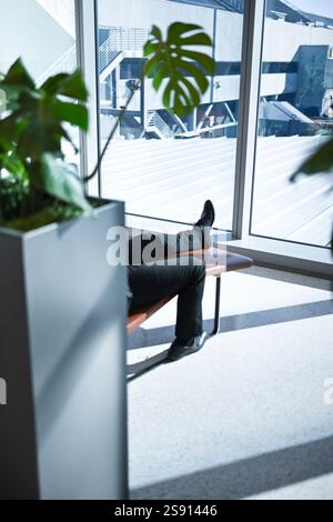 Flughafen-Lounging in der Nähe von Pflanzen Fuß sichtbare mittlere Reichweite Stockfoto