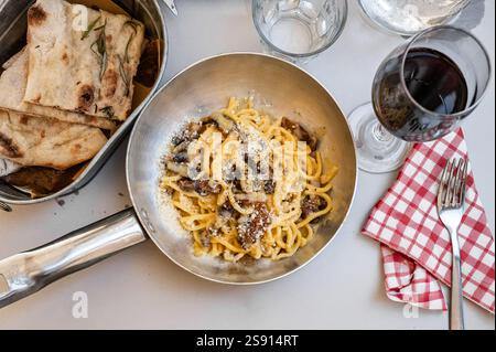 Italienische Carbonara-Pasta mit Brot und Rotwein auf einem Tisch Stockfoto