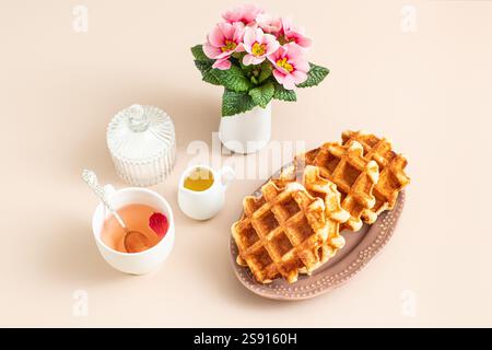 Stillleben mit Wiener Waffeln mit Tee in weichem Beige Stockfoto