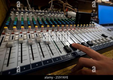 Die männliche Hand passt die Skala an die Digital Sound Workstation neben dem Router und dem Desktop an. Eine Mischkonsole zum Einrichten und Aufzeichnen von Close-u Stockfoto