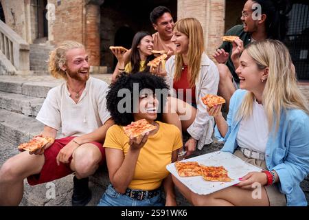 Fröhliche, multiethnische Freunde essen Pizza im Freien in urbaner Umgebung Stockfoto