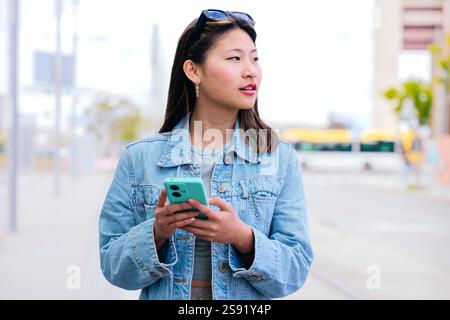 Lächelnde junge Frau, die Smartphone in der städtischen Umgebung hält Stockfoto