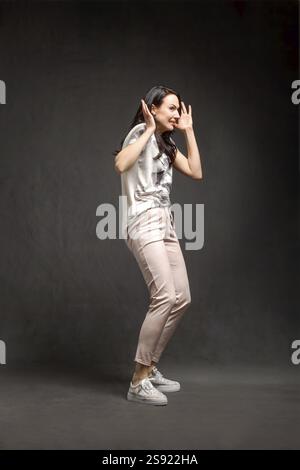 Portraet in voller Laenge von laechelnden stilvolle Frau posiert ueber grauen Hintergrund Stockfoto