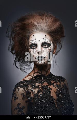 Ein Mädchen posiert in einem gruseligen Halloween-Kostüm einer Hexe mit Peircing und aufgerissenem, gemalten Gesicht Stockfoto
