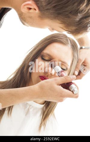 Make-up-Anwendung. Make-up Artist wendet Puder vor einem weißen Hintergrund auf. Studio-Aufnahmen Stockfoto