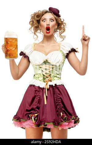 Kreatives Konzeptfoto einer Oktoberfest-Kellnerin in traditioneller bayerischer Tracht mit Bier vor weißem Hintergrund Stockfoto