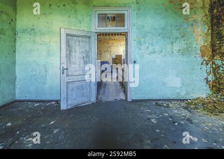Öffnen Sie die Holztür in einem baufälligen Raum mit abblätternder grüner Wandfarbe, Gefängnis H11, Lost Place, Verviers, Provinz Lüttich, Belgien, Europa Stockfoto