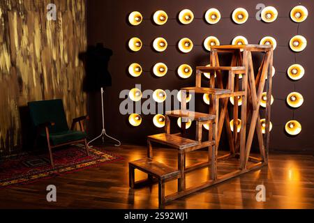Holztreppe gegen Wand aus Glühlampen. Wand aus Scheinwerfern mit großer Treppe Stockfoto